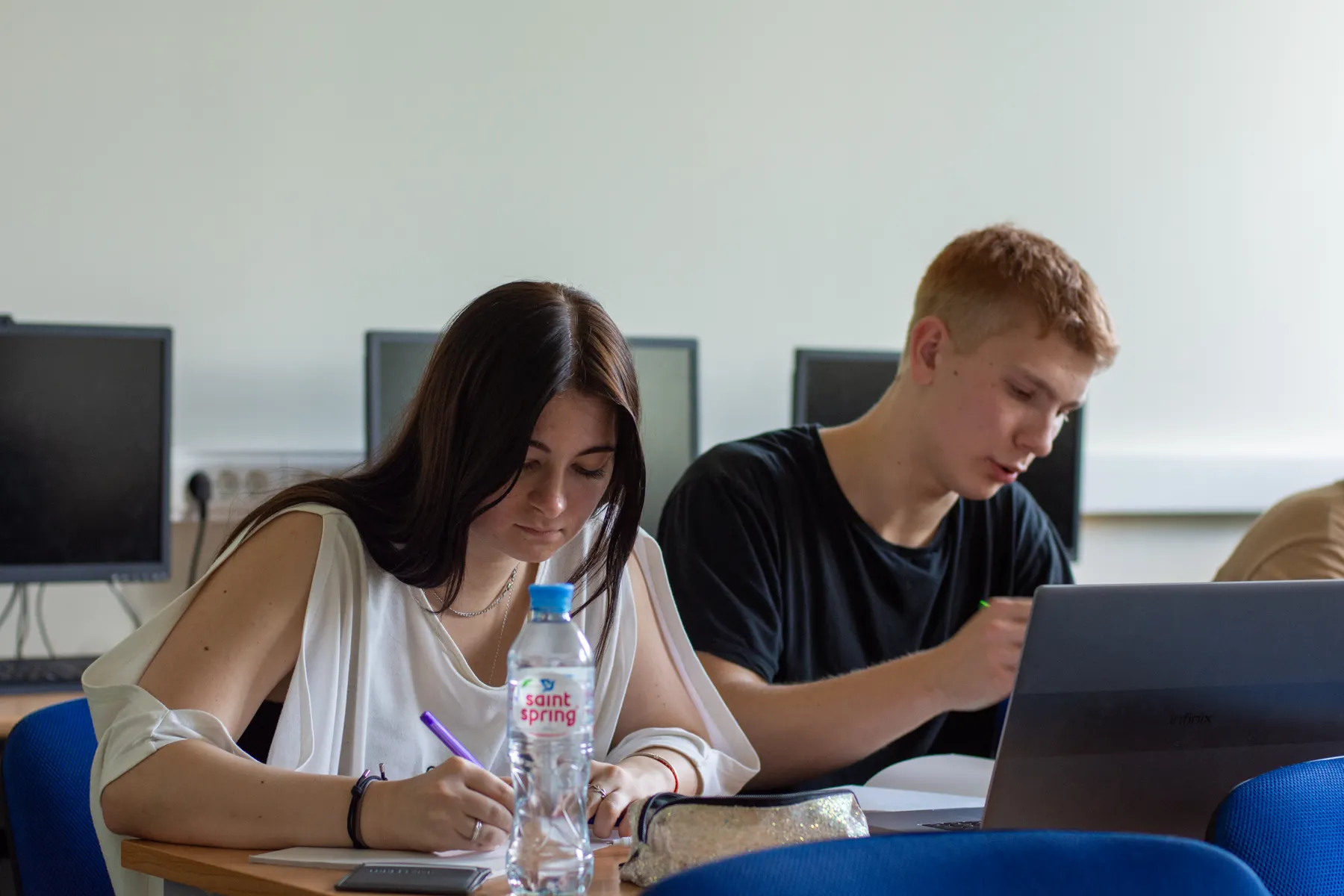Students taking notes and studying with a laptop in a computer lab
