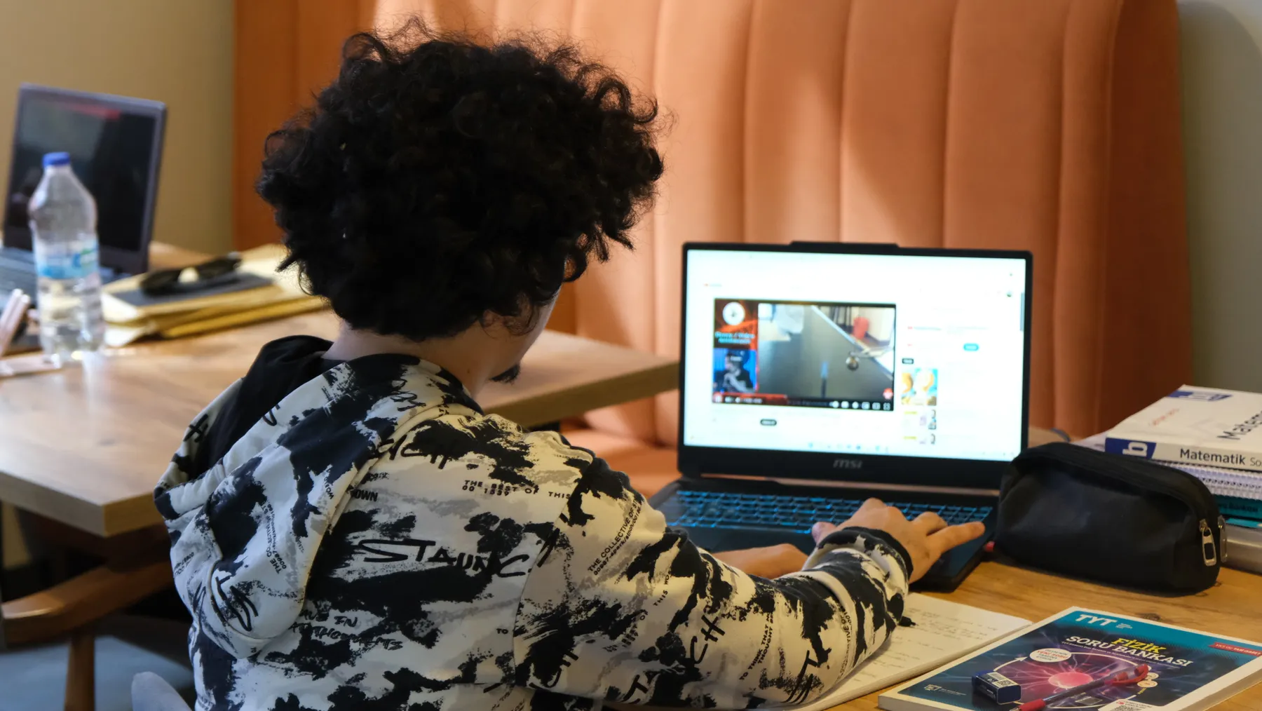 Teen student watching an online tutorial at a study desk